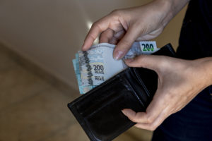 Hands With Black Wallet Putting Brazilian Money. - Barão Assessoria Contábil