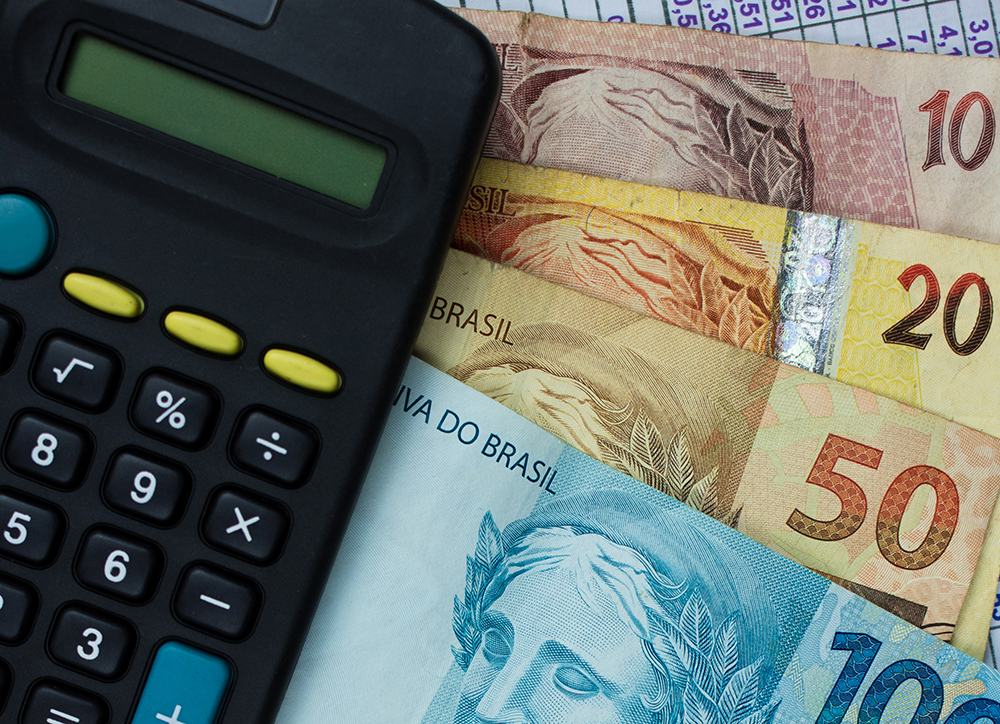 Brazilian Money With Calculator And Numerical Chart Background - Barão Assessoria Contábil