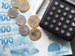 Finance Concept One Hundred Reais Bills And Coins With Calculato - Barão Assessoria Contábil